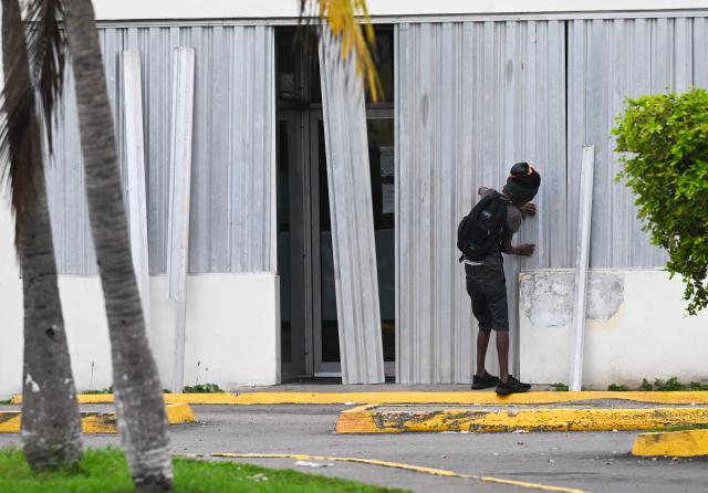A man installs storm shutters at a business in preparation for the arrival of Hurricane Melissa in Portmore, St. Catherine parish, Jamaica, on October 25, 2025. Deadly storm Melissa strengthened Saturday afternoon into a Category 1 hurricane, with rapid intensification expected over the weekend as it cut a worryingly slow course toward the Caribbean island of Jamaica, forecasters said. (Photo by Ricardo Makyn / AFP)