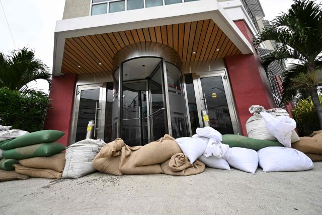 Sandbags are placed at the entrance of the Grace Kennedy building in preparation for the arrival of Hurricane Melissa in downtown Kingston, Jamaica, on October 25, 2025. Deadly storm Melissa strengthened Saturday afternoon into a Category 1 hurricane, with rapid intensification expected over the weekend as it cut a worryingly slow course toward the Caribbean island of Jamaica, forecasters said. (Photo by Ricardo Makyn / AFP)