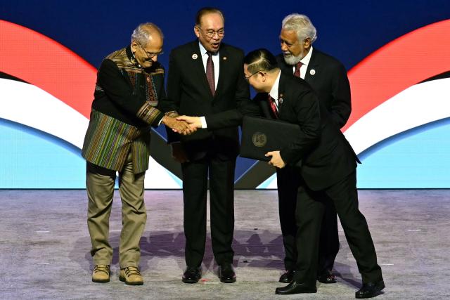 East Timor's President Jose Ramos-Horta (L) shakes hands with ASEAN Secretary-General Kao Kim Hourn, as Malaysia's Prime Minister Anwar Ibrahim (2nd L) and East Timor's Prime Minister Xanana Gusmao (back R) watch, after East Timor joined the Association of Southeast Asian Nations (ASEAN) during the ASEAN Summit in Kuala Lumpur on October 26, 2025. East Timor joined the Association of Southeast Asian Nations (ASEAN) bloc on October 26 as its 11th member state after 14 years of campaigning. (Photo by MOHD RASFAN / AFP)