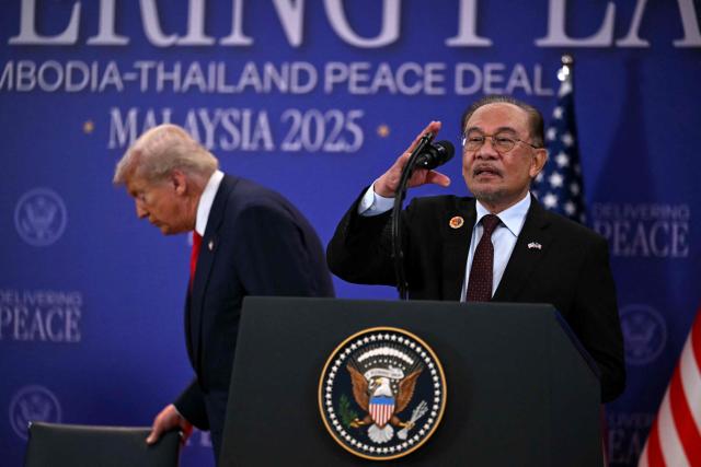 Malaysia's Prime Minister Anwar Ibrahim (R) adjusts the microphone as he prepares to speak after US President Donald Trump ahead of the ceremonial signing of a ceasefire agreement between Cambodia and Thailand on the sidelines of the 47th Association of Southeast Asian Nations (ASEAN) Summit in Kuala Lumpur on October 26, 2025. (Photo by ANDREW CABALLERO-REYNOLDS / AFP)
