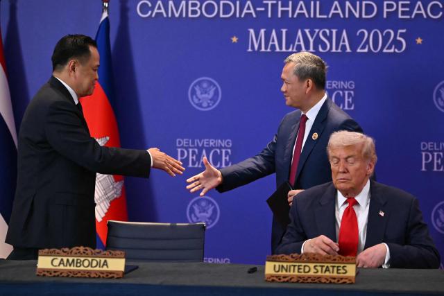 Cambodia's Prime Minister Hun Manet (C) shakes hands with Thailand's Prime Minister Anutin Charnvirakul as US President Donald Trump (R) looks on ahead of the ceremonial signing of a ceasefire agreement on the sidelines of the 47th Association of Southeast Asian Nations (ASEAN) Summit in Kuala Lumpur on October 26, 2025. (Photo by ANDREW CABALLERO-REYNOLDS / AFP)