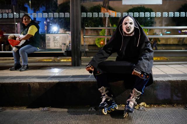 A person in costume rests during a nighttime ride ahead of the Day of the Dead ("Dia de los Muertos") celebrations in Mexico City on October 25, 2025. (Photo by Rodrigo Oropeza / AFP)