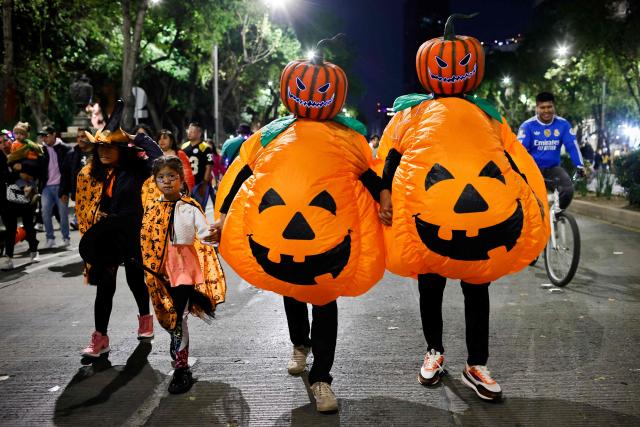 People in costumes walk during a nighttime ride ahead of the Day of the Dead ("Dia de los Muertos") celebrations in Mexico City on October 25, 2025. (Photo by Rodrigo Oropeza / AFP)