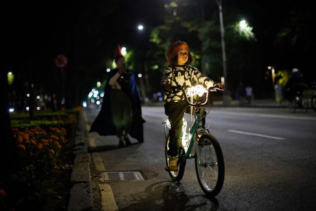A young boy participates in a nighttime ride ahead of the Day of the Dead ("Dia de los Muertos") celebrations in Mexico City on October 25, 2025. (Photo by Rodrigo Oropeza / AFP)