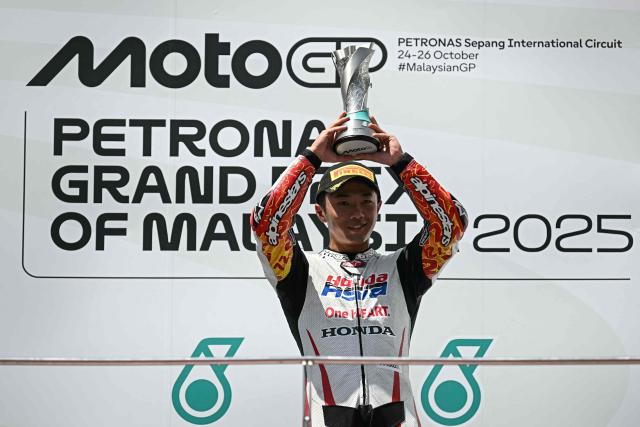Honda Team Asia team's Japanese Moto3 rider Taiyo Furusato celebrates with the trophy on the podium after winning the Moto3 race at the MotoGP Malaysian Grand Prix at the Sepang International Circuit in Sepang on October 26, 2025. (Photo by Lillian SUWANRUMPHA / AFP)