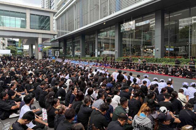 Mourners wait at Chulalongkorn Hospital for the body of Thailand's former queen Sirikit to be transported to the Grand Palace in Bangkok on October 26, 2025. The year-long funeral ceremony of Thailand's former Queen Sirikit started on October 26, with grieving royalists set to salute the procession bringing her remains to lie in state at Bangkok's Grand Palace. (Photo by Watsamon TRI-YASAKDA / AFP)