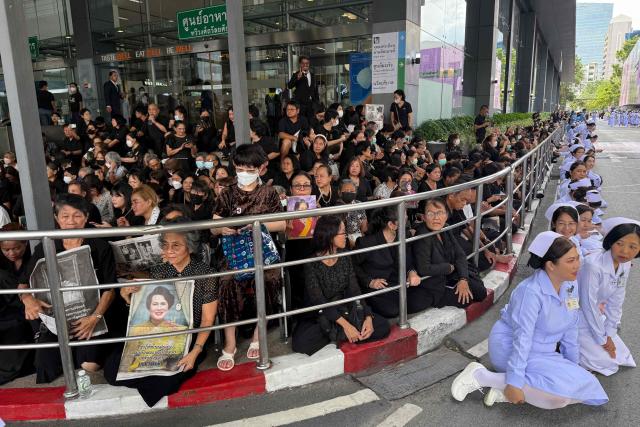 TOPSHOT - Mourners and nurses (R in white) wait at Chulalongkorn Hospital for the body of Thailand's former queen Sirikit to be transported to the Grand Palace in Bangkok on October 26, 2025. The year-long funeral ceremony of Thailand's former Queen Sirikit started on October 26, with grieving royalists set to salute the procession bringing her remains to lie in state at Bangkok's Grand Palace. (Photo by Watsamon TRI-YASAKDA / AFP)