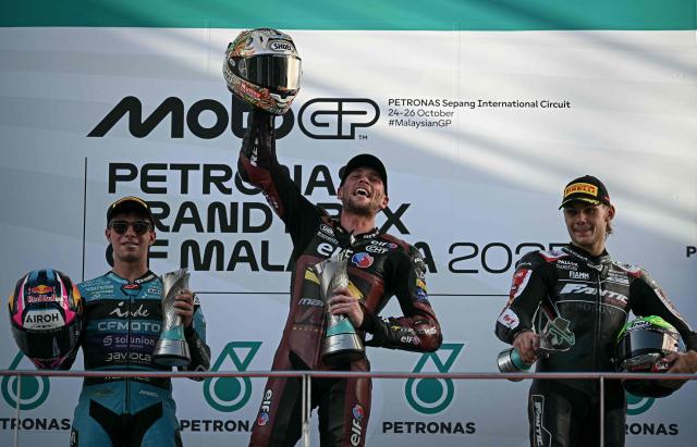 (L-R) Second-placed CFMOTO Inde Aspar Team's Colombian Moto2 rider David Alonso, winner ELF Marc VDS Raging Team's British Moto2 rider Jake Dixon and third-placed Fantic Racing Lino Sonego team's Belgian Moto2 rider Barry Baltus celebrate on the podium after the Moto2 race at the MotoGP Malaysian Grand Prix at the Sepang International Circuit in Sepang on October 26, 2025. (Photo by Lillian SUWANRUMPHA / AFP)