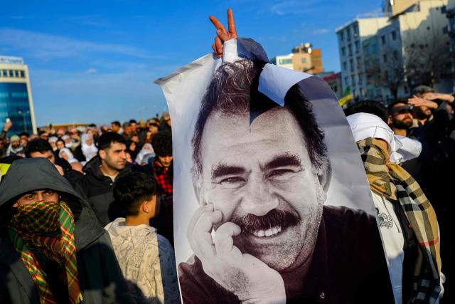 (FILES) Supporters display a poster depicting jailed leader of the Kurdistan Workers' Party (PKK) Abdullah Ocalan, after he called on the Kurdistan Workers' Party (PKK) to disarm and dissolve itself in Diyarbakir, southeastern Turkey, on February 27, 2025. The Turkish parliamentary commission overseeing the peace process with the Kurds must "immediately" meet with the PKK's jailed founder Abdullah Ocalan, one of its senior militants said on October 26, 2025. (Photo by Yasin AKGUL / AFP)