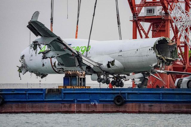 A crane hoists the main fuselage section of an ACT Airlines Boeing 747-400 cargo aircraft, wet leased by Emirates SkyCargo, out of the water in Hong Kong on October 26, 2025, after it veered off an airport runway on October 20 during landing, hitting a security patrol car and then skidding into the sea, leaving two men in the vehicle dead. (Photo by Leung Man Hei / AFP)