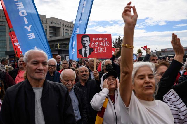A protester holds a banner with the pictures of jailed Istanbul Mayor Ekrem Imamoglu during a rally organized by the country's main opposition party, the Republican People's Party (CHP), to protest the suspension and imprisonment of Istanbul Mayor, in Istanbul on October 26, 2025. Istanbul's opposition mayor was detained on March 19, 2025 and jailed several days later as part of a corruption investigation, a move that sparked Turkey's worst street protests in over a decade. (Photo by Yasin AKGUL / AFP)