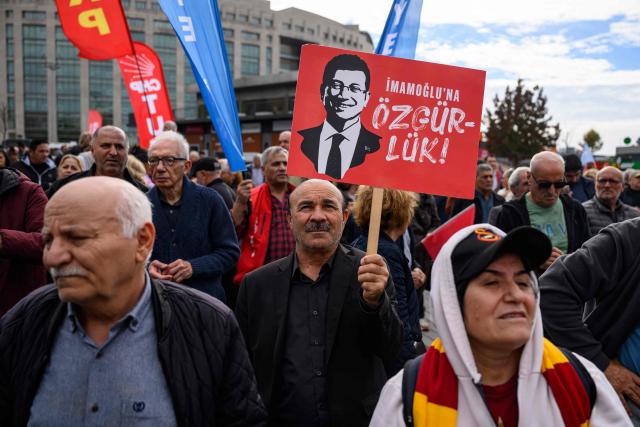 A protester holds a banner with the pictures of jailed Istanbul Mayor Ekrem Imamoglu during a rally organized by the country's main opposition party, the Republican People's Party (CHP), to protest the suspension and imprisonment of Istanbul Mayor, in Istanbul on October 26, 2025. Istanbul's opposition mayor was detained on March 19, 2025 and jailed several days later as part of a corruption investigation, a move that sparked Turkey's worst street protests in over a decade. (Photo by Yasin AKGUL / AFP)