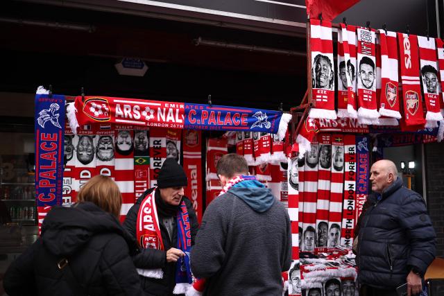 Fans buy goods from a merchadise stall near to the ground ahead of the English Premier League football match between Arsenal and Crystal Palace at the Emirates Stadium in London on October 26, 2025. (Photo by HENRY NICHOLLS / AFP)