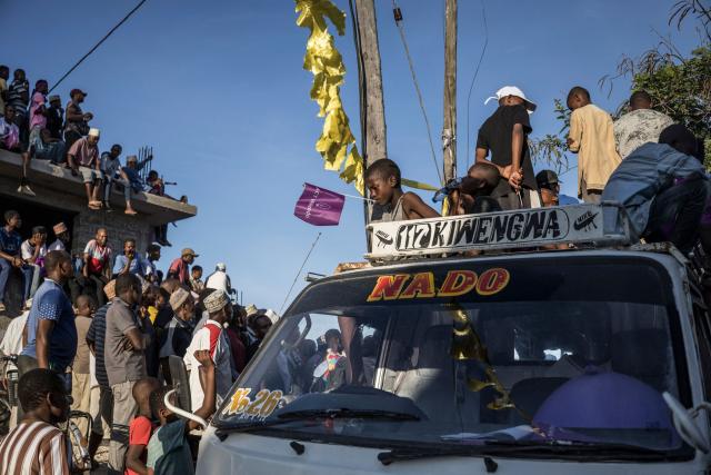 TOPSHOT - A boy holds a flag in his mouth as supporters of Othman Masoud Othman the presidential candidate for the opposition ACT-Wazalendo (Alliance for Change and Transparency) stand on a truck and on an unfinished building as they gather during the campaign closing rally in Stone Town, on October 26, 2025. (Photo by MARCO LONGARI / AFP)