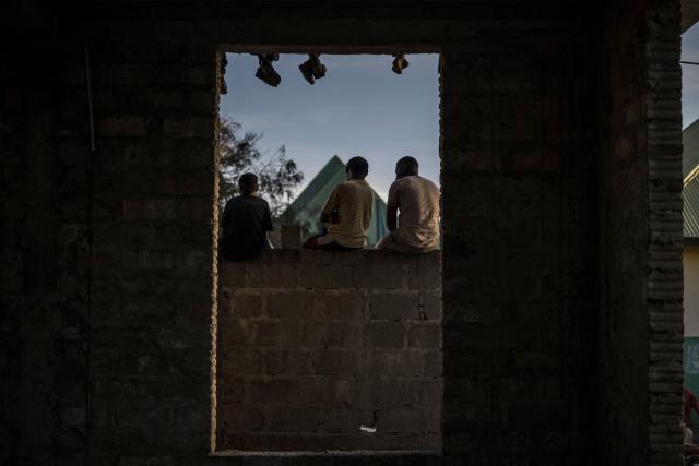 Supporters of Othman Masoud Othman the presidential candidate for the opposition ACT-Wazalendo (Alliance for Change and Transparency) stand on a wall of an unfinished building as they gather during the campaign closing rally in Stone Town, on October 26, 2025. (Photo by MARCO LONGARI / AFP)
