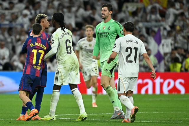 Barcelona's Spanish forward #10 Lamine Yamal (2L) argues with Real Madrid's Belgian goalkeeper #01 Thibaut Courtois (2R) during the Spanish league football match between Real Madrid CF and FC Barcelona at the Santiago Bernabeu stadium in Madrid on October 26 , 2025. (Photo by JAVIER SORIANO / AFP)
