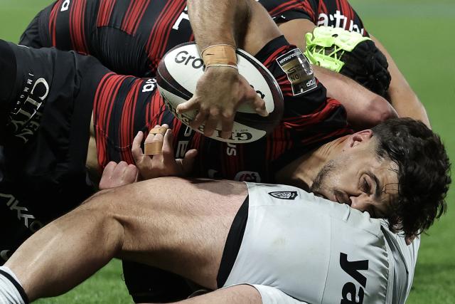 Toulouse's French fly-half Romain Ntamack (C) is tackled as he dives to score Toulouse's third try during the French Top14 rugby union match between Stade Toulousain Rugby (Toulouse) and Rugby Club Toulonnais (Toulon) at the Ernest-Wallon stadium in Toulouse, south-western France, on October 26, 2025. (Photo by Valentine CHAPUIS / AFP)