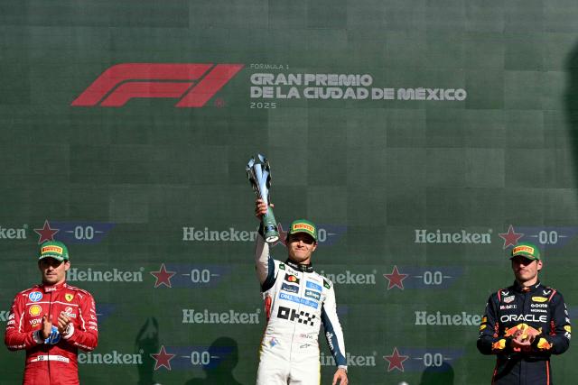 McLaren's British driver Lando Norris lifts the trophy on the podium next Ferrari's Monegasque driver Charles Leclerc and Red Bull Racing's Dutch driver Max Verstappen after winning the Mexico City Formula One Grand Prix at the Hermanos Rodriguez racetrack in Mexico City on October 26, 2025. (Photo by Yuri CORTEZ / AFP)