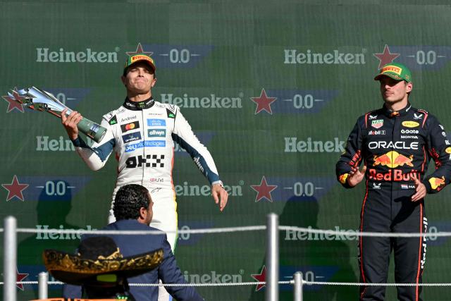 McLaren's British driver Lando Norris lifts the trophy on the podium next to Red Bull Racing's Dutch driver Max Verstappen after winning the Mexico City Formula One Grand Prix at the Hermanos Rodriguez racetrack in Mexico City on October 26, 2025. (Photo by Yuri CORTEZ / AFP)