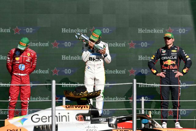 McLaren's British driver Lando Norris lifts the trophy on the podium next to Ferrari's Monegasque driver Charles Leclerc and Red Bull Racing's Dutch driver Max Verstappen after winning the Mexico City Formula One Grand Prix at the Hermanos Rodriguez racetrack in Mexico City on October 26, 2025. (Photo by Yuri CORTEZ / AFP)