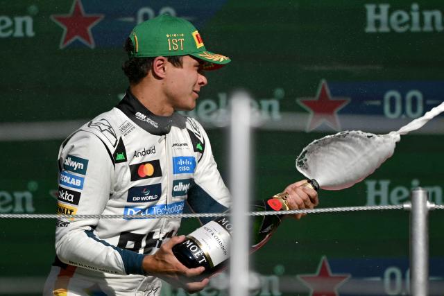 McLaren's British driver Lando Norris sprays the victory Champagne on the podium after winning the Mexico City Formula One Grand Prix at the Hermanos Rodriguez racetrack in Mexico City on October 26, 2025. (Photo by CARL DE SOUZA / AFP)
