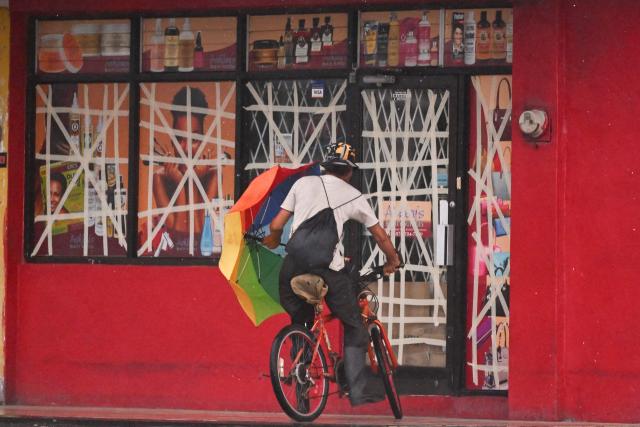 A cyclist rides up to a store to seek shelter from Hurricane Mellisa in Portmore on October 26, 2025. Hurricane Melissa was cutting a deadly path in the Caribbean on the night of October 25, with rapid intensification expected over the weekend as it took a worryingly slow course toward Jamaica and the island of Hispaniola, forecasters said. (Photo by Ricardo Makyn / AFP)