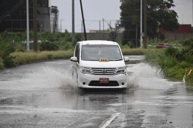 A motorist drives along flooded Michael Manley Boulevard in Kingston, Jamaica, as Jamaica starts to feel the effects of Hurricane Mellisa on October 26, 2025. Hurricane Melissa, already a major category 4 storm, gathered steam Sunday as it took aim at Jamaica and other parts of the Caribbean, with forecasters predicting catastrophic flooding and urging residents to seek shelter immediately. (Photo by Ricardo Makyn / AFP)