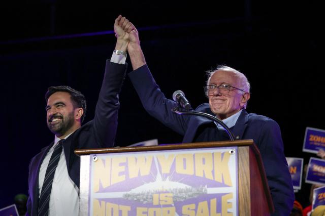New York City mayoral candidate Zohran Mamdani (L) holds hands with US Senator Bernie Sanders (I-VT) during a campaign rally at Forest Hills Stadium in the Queens borough of New York City on October 26, 2025. New Yorkers will cast their votes for mayor on November 4, 2025. Mamdani, the Democratic candidate, is the current frontrunner ahead of former New York Governor and independent candidate Andrew Cuomo and Republican candidate Curtis Sliwa. (Photo by ANGELA WEISS / AFP)