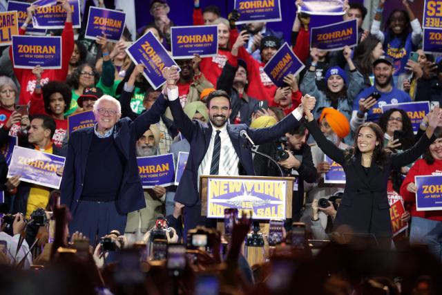 New York City mayoral candidate Zohran Mamdani (C) holds hands with US Senator Bernie Sanders (I-VT) (L) and US Representative Alexandria Ocasio-Cortez (D-NY) at the end of a campaign rally at Forest Hills Stadium in the Queens borough of New York City on October 26, 2025. New Yorkers will cast their votes for mayor on November 4, 2025. Mamdani, the Democratic candidate, is the current frontrunner ahead of former New York Governor and independent candidate Andrew Cuomo and Republican candidate Curtis Sliwa. (Photo by ANGELA WEISS / AFP)