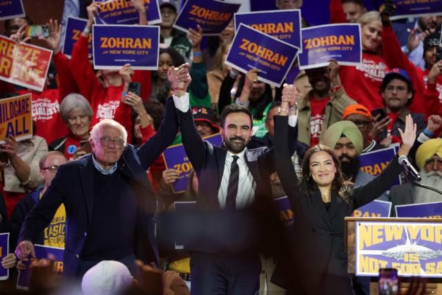 New York City mayoral candidate Zohran Mamdani (C) holds hands with US Senator Bernie Sanders (I-VT) (L) and US Representative Alexandria Ocasio-Cortez (D-NY) at the end of a campaign rally at Forest Hills Stadium in the Queens borough of New York City on October 26, 2025. New Yorkers will cast their votes for mayor on November 4, 2025. Mamdani, the Democratic candidate, is the current frontrunner ahead of former New York Governor and independent candidate Andrew Cuomo and Republican candidate Curtis Sliwa. (Photo by ANGELA WEISS / AFP)