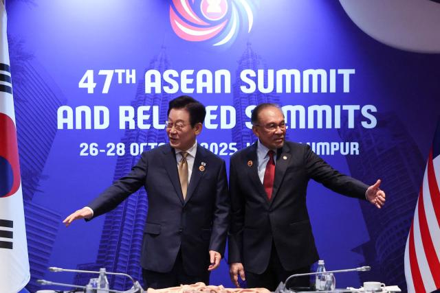 Malaysia's Prime Minister Anwar Ibrahim (R) and South Korea's President Lee Jae Myung gesture during a bilateral meeting on the sidelines of the 47th Association of Southeast Asian Nations (ASEAN) Summit in Kuala Lumpur on October 27, 2025. (Photo by Hasnoor Hussain / POOL / AFP)