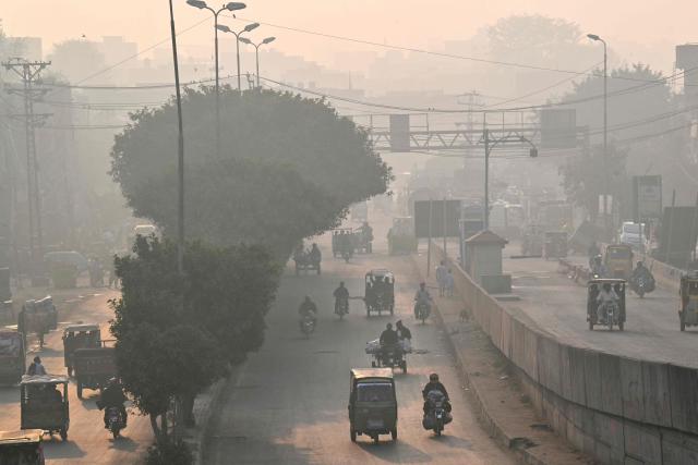 Commuters drive along a road amid dense smog in Lahore on October 27, 2025. (Photo by Arif ALI / AFP)
