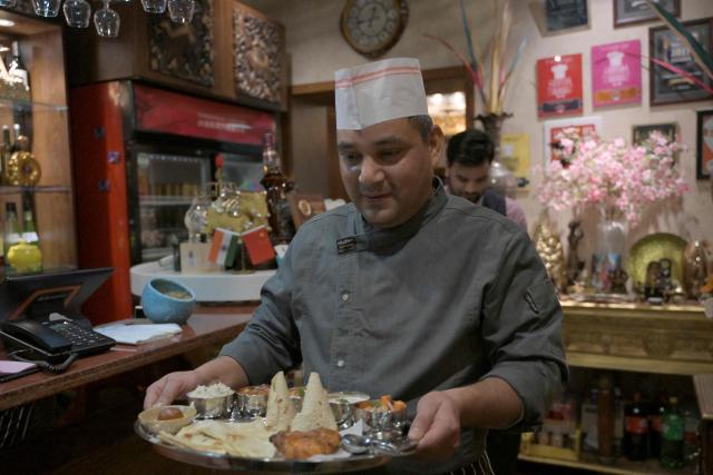 A waiter carries a thali tray with an assortment of Indian food at an Indian restaurant in Beijing on October 27, 2025. (Photo by Adek BERRY / AFP)