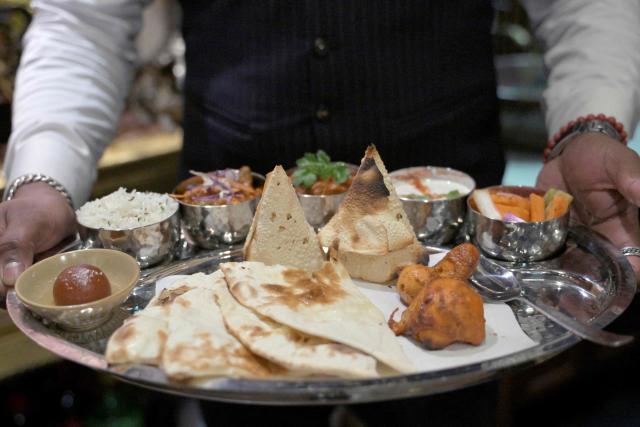 A waiter carries a thali tray with an assortment of Indian food at an Indian restaurant in Beijing on October 27, 2025. (Photo by Adek BERRY / AFP)
