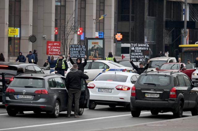 Activists hold placards as they demonstrate among stopped cars at Independence Square in Kyiv on October 27, 2025, during a "National Minute of Silence for Those Who Died" as a result of Russia's armed aggression against Ukraine. (Photo by Sergei SUPINSKY / AFP)