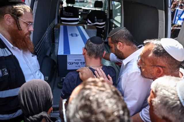 Mourners touch the coffin placed in the back of a van as they bid farewell during  the funeral procession of Yossi Sharabi, who was killed in captivity after being taken by the Palestinian militant group Hamas during their October 7, 2023 attacks, in the central Israeli city of Rishon Letzion on October 27, 2025. Sharabi's remains were returned to Israel under a new truce brokered by US President Donald Trump. (Photo by FADEL SENNA / AFP)