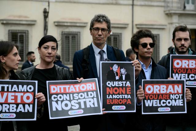 Riccardo Magi (C), secretary of Italian pro-Europe party +Europa (More Europe), stages a protest against Hungary's Prime Minister Viktor Orban in front of Palazzo Chigi prior a meeting with Italy's Prime Minister, Giorgia Meloni, in Rome on October 27, 2025. Placards read "Dictator with our money" "This is not our Europe" "Orban you are not welcome". (Photo by Tiziana FABI / AFP)