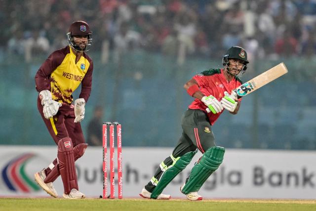 Bangladesh's Tanzid Hasan (R) plays a shot as West Indies' captain Shai Hope watches during the first Twenty20 international cricket match between Bangladesh and West Indies at a stadium in Chittagong on October 27, 2025. (Photo by MUNIR UZ ZAMAN / AFP)