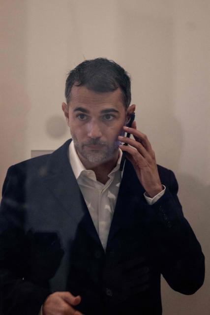 French author Aurélien Poirson-Atlan also known as Zoe Sagan is seen through a window as he speaks on the phone during a break in his trial with nine other persons accused of sexist cyber-harassment of Brigitte Macron, in Paris, on October 27, 2025. Ten people go on trial in Paris on October 27, 2025 for sexist cyber-harassment of Brigitte Macron, in the latest case sparked by unsubstantiated gender claims thrown at the wife of the French President for years by some in France and beyond. (Photo by Guillaume BAPTISTE / AFP)