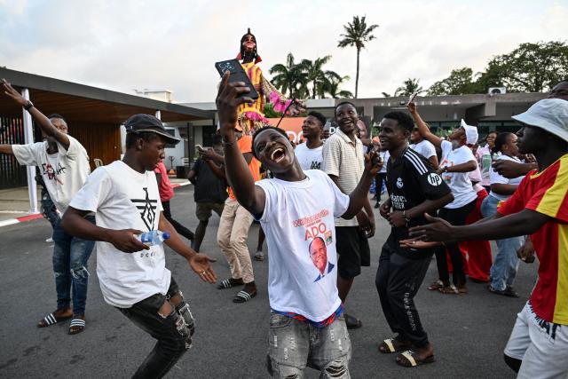 Supporters of Ivory Coast's President and presidential candidate for the Rally of Houphouetists for Democracy and Peace (RHDP) party Alassane Ouattara celebrate winning the presidential election at the party headquarters in Abidjan on October 27, 2025. Ivory Coast's President Alassane Ouattara has won a fourth term, securing a crushing 89.77 percent in a vote which his two greatest rivals were barred from, the electoral commission said on October 27, 2025. Nearly nine million voters were eligible to cast their ballot Saturday in the world's top cocoa producer, which has resisted coups and jihadist attacks plaguing much of west Africa but which saw tensions soar and deadly violence in the run-up to the election. (Photo by Sia KAMBOU / AFP)