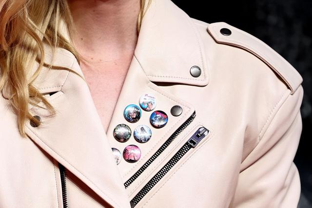 Badges worn by US actor Elle Fanning are pictured as she walks the red carpet upon arrival to attend the UK special screening of "Predator: Badlands" at the BFI IMAX in London, on October 27, 2025. (Photo by HENRY NICHOLLS / AFP)
