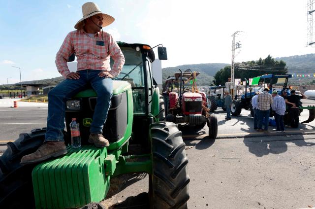 A farmer sits on a tractor blocking the highway to Nogales to protest the price of corn and against the federal government in Zapopan, Jalisco state, Mexico on October 27, 2025. (Photo by ULISES RUIZ / AFP)
