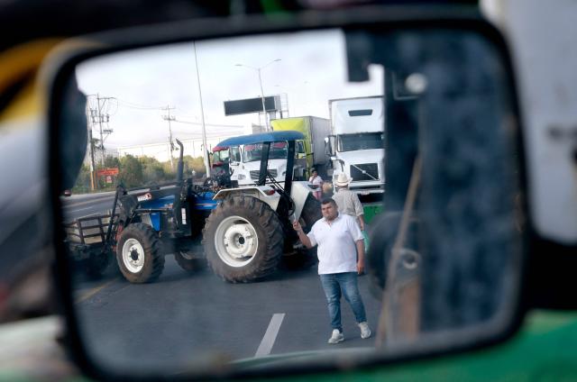 Farmers are reflected on a mirror as they block the highway to Nogales to protest the price of corn and against the federal government in Zapopan, Jalisco state, Mexico on October 27, 2025. (Photo by ULISES RUIZ / AFP)