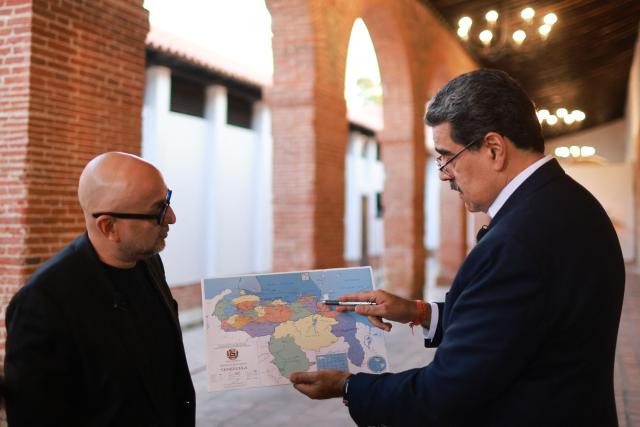 This handout picture released by Venezuelan Presidency shows Venezuela's President Nicolas Maduro (R) pointing to a map of Venezuela during an official TV show in Caracas on October 27, 2025. Venezuelan President Nicolas Maduro on October 27, announced he had suspended an energy agreement with Trinidad and Tobago in response to the neighboring island nation's welcoming of a US warship. (Photo by Marcelo Garcia / Venezuelan Presidency / AFP)