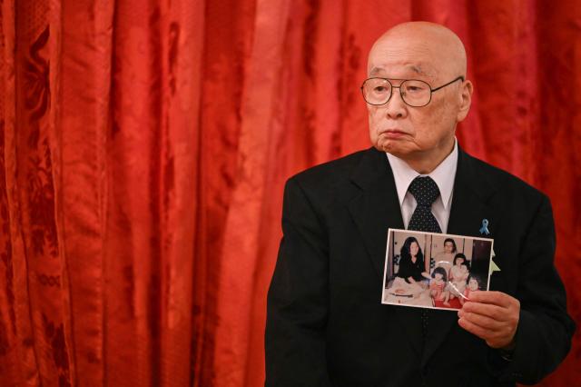 A family member of Japanese citizens abducted by North Korea holds a photograph before a meeting with US President Donald Trump and Japan's Prime Minister Sanae Takaichi at the Akasaka State Guest House in Tokyo on October 28, 2025. (Photo by ANDREW CABALLERO-REYNOLDS / AFP)