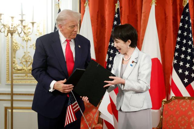 US President Donald Trump and Japan's Prime Minister Sanae Takaichi prepare to pose during a signing ceremony for a document on the implementation of the US-Japan trade deal at the Akasaka State Guest House in Tokyo on October 28, 2025. (Photo by Kiyoshi Ota / POOL / AFP)