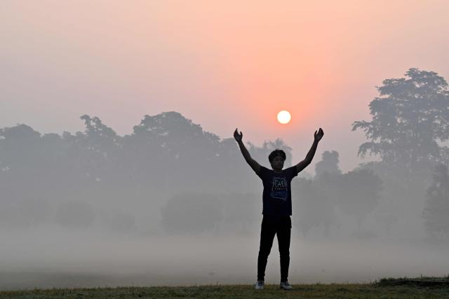 A man stretches at a park amid dense smog in Lahore on October 28, 2025. (Photo by Arif ALI / AFP)