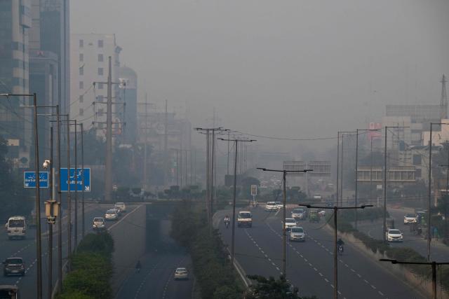 Commuters drive along a road amid dense smog in Lahore on October 28, 2025. (Photo by Arif ALI / AFP)