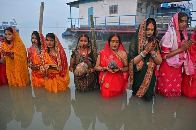 Hindu devotees offer prayers to the Sun god on the occasion of 'Chhath Puja' festival, along the banks of river Brahmaputra in Guwahati on October 28, 2025. (Photo by Biju BORO / AFP)