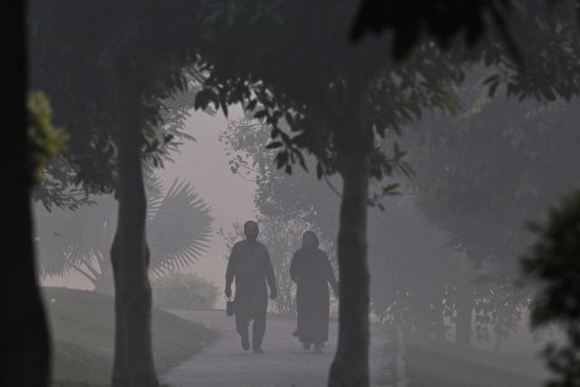People walk at a park amid dense smog in Lahore on October 28, 2025. (Photo by Arif ALI / AFP)